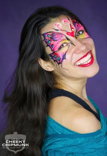 A photo of a woman with a butterfly painted around her eyes and forehead.