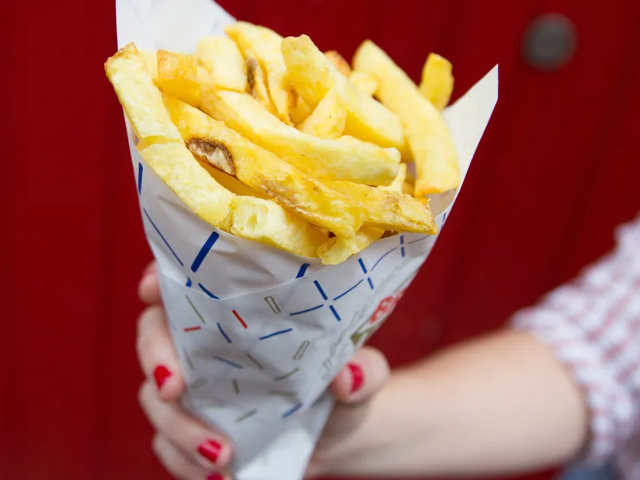 A photo of a paper cone full of fries.